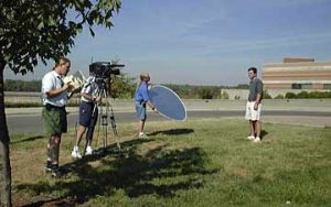 The KET crew video tapes field trip host Chip Polston in front of the Falls of the Ohio Interpretive Center.
